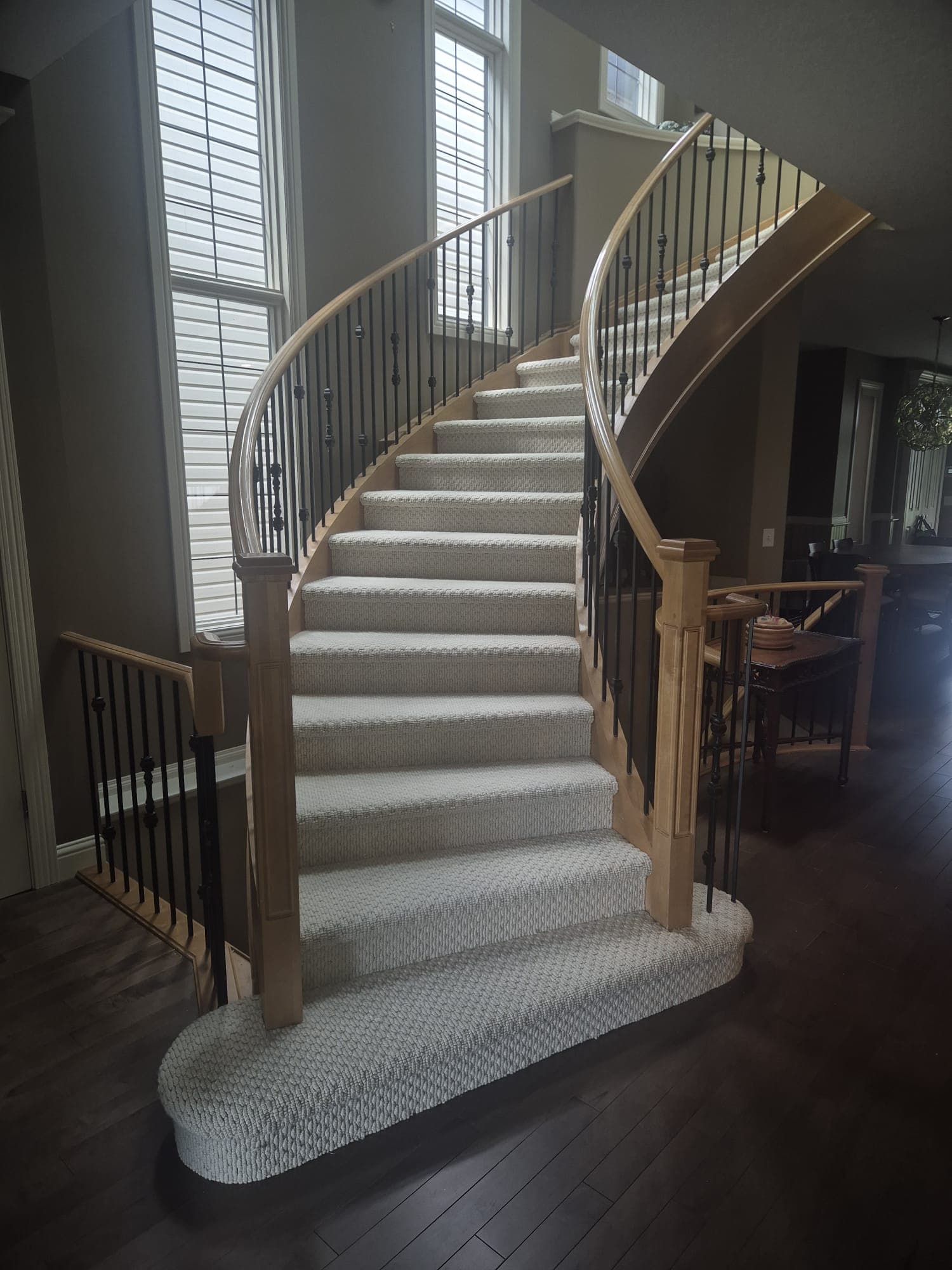Curved staircase finished in oat wool berber carpet with a dark wood railing